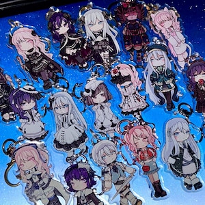 May include: A selection of anime-style character keyrings. Each keyring showcases a unique character design with detailed outfits and hairstyles. The keyrings are made of clear acrylic and have gold-coloured key rings.