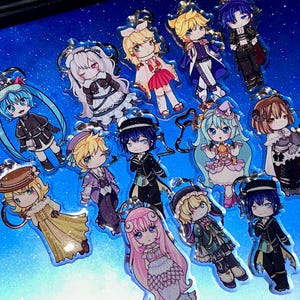 May include: A selection of anime-style character keyrings. Each keyring showcases a unique character design with vibrant colours and detailed outfits. The keyrings are made of clear acrylic and have silver-coloured key rings.
