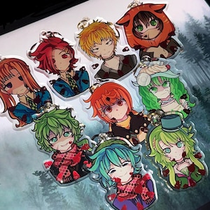 May include: Nine anime-style acrylic keyrings showcasing diverse characters with vibrant hair and clothing. Each keyring has a silver metal loop and features a character with a unique expression and design, with a bloody theme.