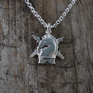 May include: A silver necklace with a pendant featuring a chess knight head with lightning bolts on either side.