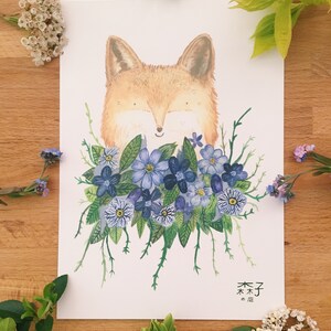 May include: A watercolor illustration of a fox with blue flowers. The fox is looking down and smiling. The flowers are arranged around the fox's head. The illustration is on a white background. The text "森子" is written in Japanese at the bottom of the illustration.
