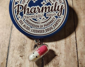 May include: A blue and white Pharmily badge reel with a smiling pill charm. The badge reel has text that reads "A group of people who have bonded together...Pharmily...Profession of Pharmacy...Licensed Drug Cartel."