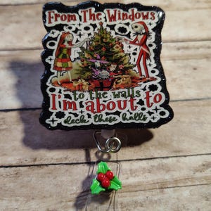 Könnte beinhalten: Ein schwarzes Ausweis-Jojo mit einem weihnachtlichen Design mit Figuren aus The Nightmare Before Christmas. Der Text lautet "From The Windows to the walls I'm about to deck these halls." Das Jojo hat einen transparenten Kunststoffriemen und einen Stechpalmen-Akzent.