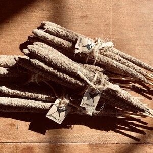 May include: A bundle of natural incense sticks tied together with twine. The sticks are made of a light brown material and have a rough texture. The sticks are labelled with the word "Artefakto" on a small tag.