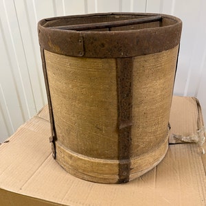 May include: A vintage wooden bucket with a metal rim and bands. The bucket is made of wood and has a rustic appearance. The metal rim and bands are rusty and have a worn look.