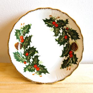 Round, Christmas-themed trinket dish made by Rosina China Co Ltd. The pattern is known as Queen's Yuletide and is a striking graphic of holly, berries and pine cones.