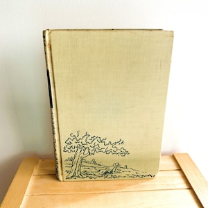 May include: A vintage hardcover book with a light green cover and a black and green illustration of a tree on the bottom right corner.