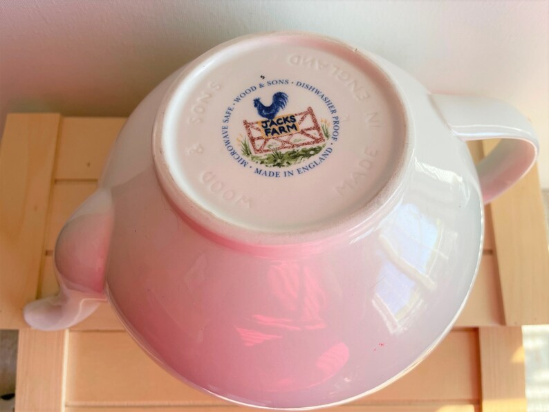 May include: White ceramic teapot with a rooster and farm scene on the bottom. The text reads "Microwave Safe - Wood & Sons - Dishwasher Proof - Made in England - Jacks Farm".