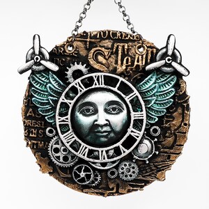 May include: A steampunk-style wall hanging featuring a clock face with a moon face, surrounded by gears, wings, and propellers. The clock face has Roman numerals and is set against a textured, bronze-colored background. The text "TO CREAT" is visible.