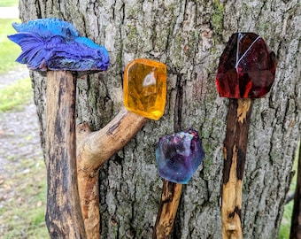 May include: Four walking sticks with different resin tops. One top is a blue dragon head, one is a yellow gem, one is a purple gem, and one is a red gem.