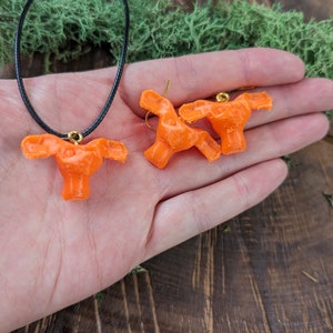 May include: A set of orange anatomical earrings and a necklace. The earrings and necklace are shaped like the human uterus.