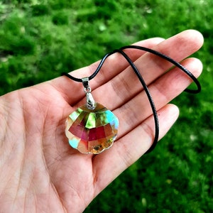 May include: A silver necklace with a black cord and a iridescent crystal seashell pendant.