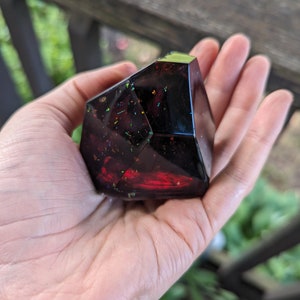 May include: A dark red, faceted, geometric resin paperweight with iridescent glitter embedded throughout.