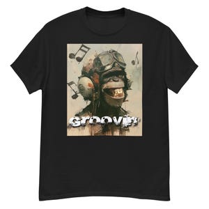 May include: A black short-sleeve t-shirt featuring a graphic print of a chimpanzee wearing vintage aviator goggles and headphones. The design includes floating musical notes and the text "groovin'" in a distressed white font at the bottom.