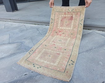 May include: A beige and pink runner rug with a geometric pattern. The rug has a fringe border and is folded in half.