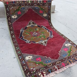 Puede incluir: Una alfombra vintage roja, verde y marr&oacute;n con un patr&oacute;n floral y flecos. La alfombra tiene un medall&oacute;n central con fondo marr&oacute;n y un dise&ntilde;o floral.