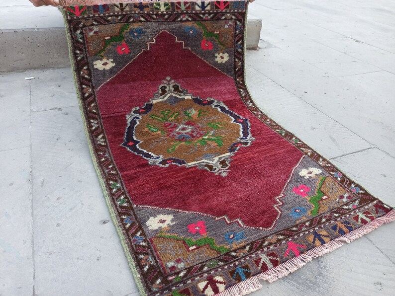 Puede incluir: Una alfombra vintage roja, verde y marr&oacute;n con un patr&oacute;n floral y flecos. La alfombra tiene un medall&oacute;n central con fondo marr&oacute;n y un dise&ntilde;o floral.