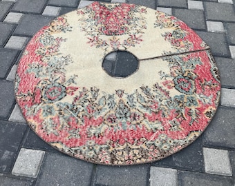 Pode incluir: Saia de árvore redonda, estilo vintage, com abertura central. A saia apresenta um fundo creme com um padrão floral em tons de vermelho, rosa e verde-azulado. As bordas são finalizadas com uma borda mais escura, criando um visual clássico e decorativo.