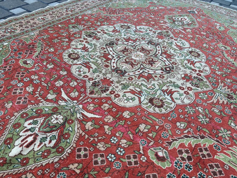May include: A detailed, antique rug with a central medallion design. The rug features a rich red background with intricate patterns in shades of green, brown, and cream. The border has a complementary design, creating a cohesive and ornate look.