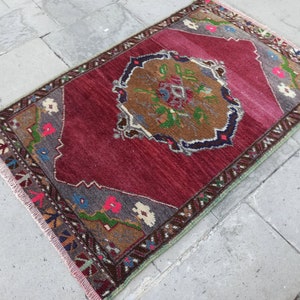 Puede incluir: Una alfombra vintage roja, verde y marr&oacute;n con un patr&oacute;n floral y bordes con flecos.