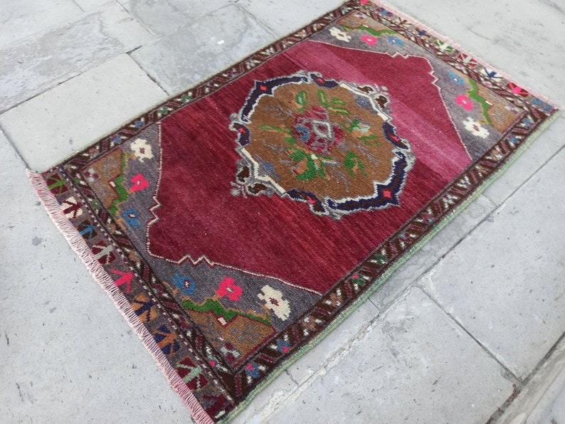 Puede incluir: Una alfombra vintage roja, verde y marr&oacute;n con un patr&oacute;n floral y bordes con flecos.