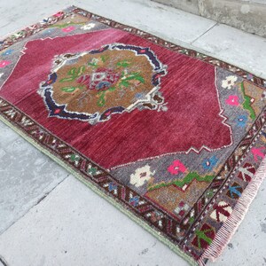Puede incluir: Una alfombra roja vintage con un patr&oacute;n floral en tonos marrones, verdes, azules y rosas. La alfombra tiene un borde de flecos y mide aproximadamente 90 cm por 120 cm.