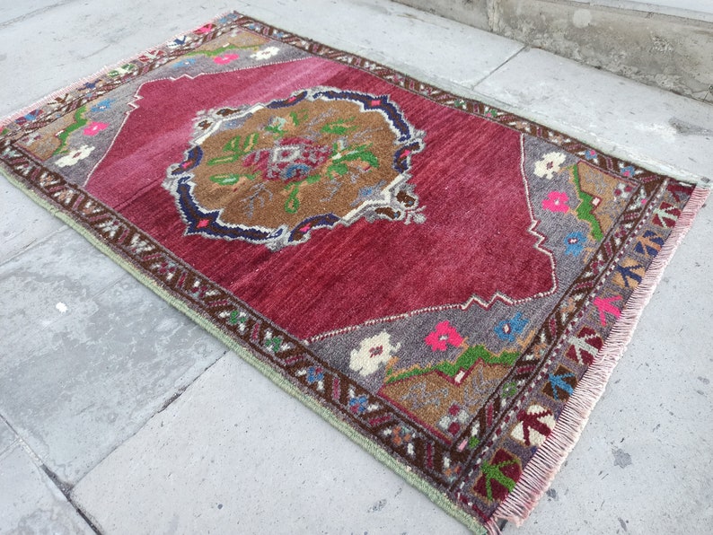 Puede incluir: Una alfombra roja vintage con un patr&oacute;n floral en tonos marrones, verdes, azules y rosas. La alfombra tiene un borde de flecos y mide aproximadamente 90 cm por 120 cm.
