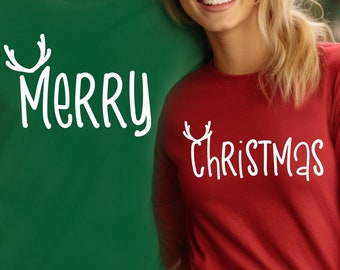Könnte beinhalten: Ein Paar trägt passende Langarmshirts mit Weihnachtsmotiv. Das Shirt des Mannes ist grün mit dem Wort "Merry" und Rentiergeweih. Das Shirt der Frau ist rot mit dem Wort "Christmas" und Rentiergeweih.