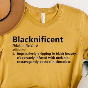 May include: A mustard yellow t-shirt with the word "Blacknificent" defined as "impressively dripping in black beauty, elaborately infused with melanin, extravagantly bathed in chocolate."