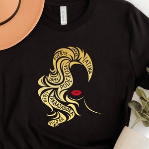 May include: Black t-shirt with a gold silhouette of a woman's head with the words "Mujer, Trabajadora, Poder, Dama, Rosa, Fuerte, Capaz, Latina" surrounding her head.