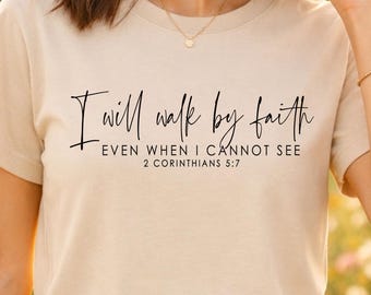May include: Beige short-sleeve t-shirt with the text "I will walk by faith, even when I cannot see, 2 Corinthians 5:7" in black script. The shirt is made of a soft material.