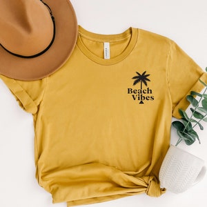 May include: A mustard yellow t-shirt with a black palm tree graphic and the text "Beach Vibes".