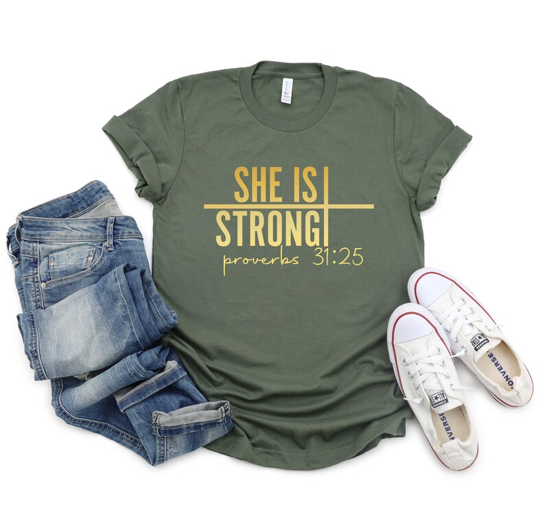 May include: A green t-shirt with the text "She is Strong" and "Proverbs 31:25" in gold lettering.