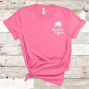May include: Pink t-shirt with a white palm tree graphic and the text "Beach Vibes".