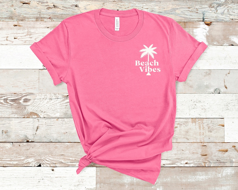 May include: Pink t-shirt with a white palm tree graphic and the text "Beach Vibes".