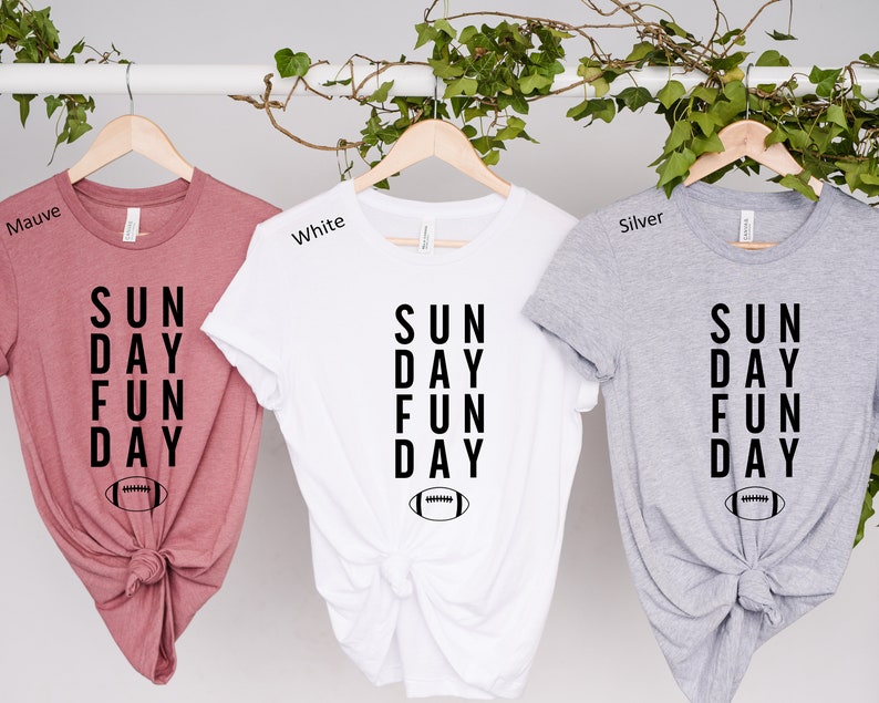 Pu&ograve; includere: Tre magliette in malva, bianco e argento con il testo "SUN DAY FUN DAY" e una grafica di un pallone da calcio.