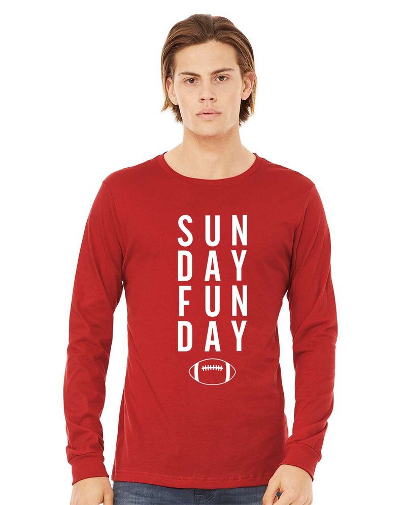 Pu&ograve; includere: Maglietta a maniche lunghe rossa con testo bianco che recita "SUNDAY FUN DAY" e una grafica di un pallone da calcio bianco.