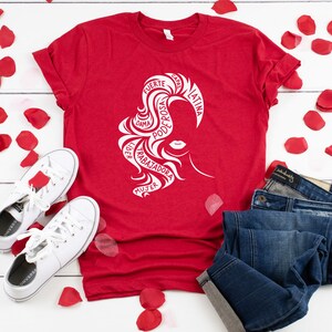 May include: Red t-shirt with a white silhouette of a woman's head with the words "FUERTE, CAPAZ, LATINA, PODEROSA, DAMA, LIDER, TRABAJADORA, MUJER" in a circle around her head.