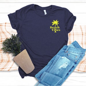 May include: A navy blue t-shirt with a yellow palm tree and the text "Beach Vibes" on the front.