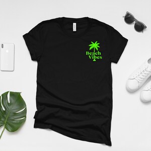 May include: Black t-shirt with a green palm tree and the text "Beach Vibes" on the front.