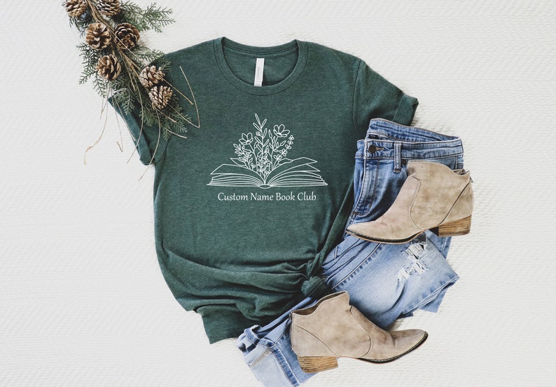 May include: A dark green t-shirt with a white outline of an open book with flowers growing out of it. The text "Custom Name Book Club" is printed below the book.