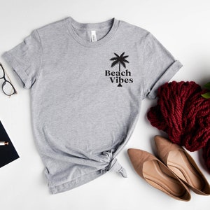 May include: A gray t-shirt with a palm tree graphic and the text "Beach Vibes" printed on the front.
