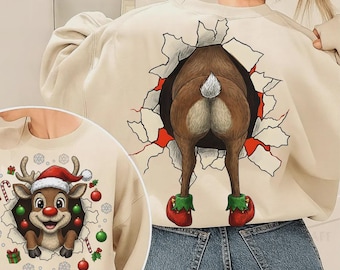 May include: Beige sweatshirt with a reindeer design. The back features a reindeer's rear end bursting through a wall, while the front shows a reindeer face with a Santa hat. Christmas-themed apparel.