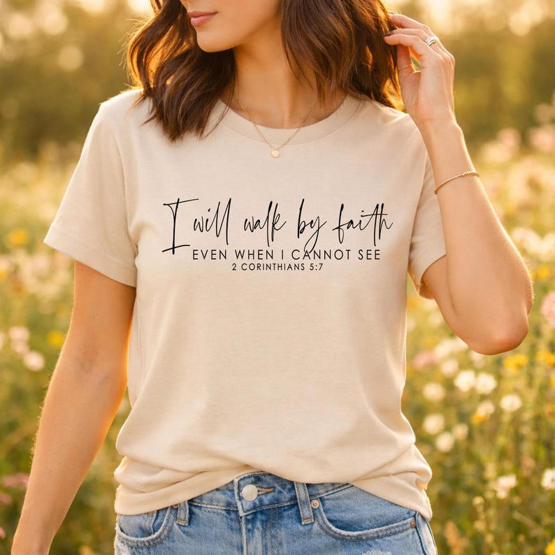 May include: Beige short-sleeve t-shirt with the text "I will walk by faith, even when I cannot see, 2 Corinthians 5:7" in black script. The shirt is made of a soft material.