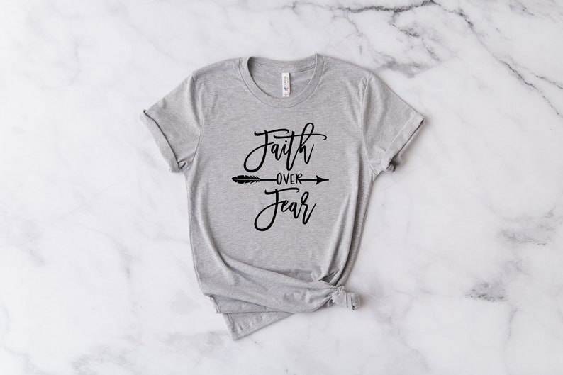May include: A gray t-shirt with the text "Faith over Fear" in black script with an arrow pointing to the right.