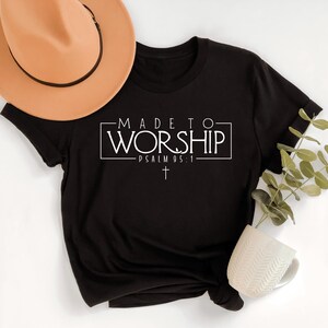 Puede incluir: Camiseta negra con texto blanco que dice "MADE TO WORSHIP - PSALM 95:1" con una peque&ntilde;a cruz debajo del texto.