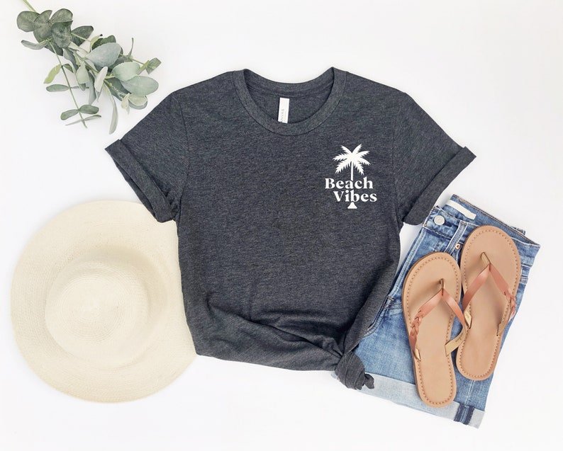May include: A dark gray t-shirt with a white palm tree and the text "Beach Vibes" printed on the front.