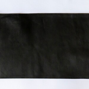 May include: A black leather placemat with stitched edges.
