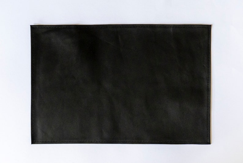 May include: A black leather placemat with stitched edges.