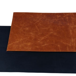 May include: Two placemats, one brown and one black. The brown placemat has a textured leather-like finish. The black placemat is smooth.